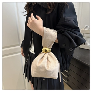 Détail du sac seau en daim beige avec un fermoir en métal doré en forme de galet