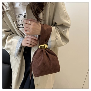 Détail d'un sac seau en daim marron avec une grande boucle en métal doré poli