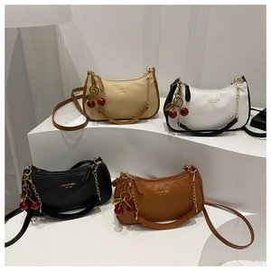 Variety of four textured leather shoulder bags with cherry charms on a white display stand