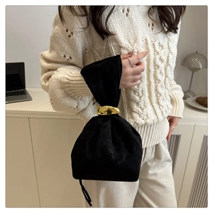 Détail d'un sac seau en suédine noire avec une poignée anneau en métal doré minimaliste