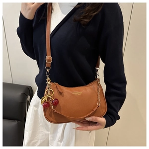 Brown lychee leather shoulder bag with gold logo and cute cherry charm on model