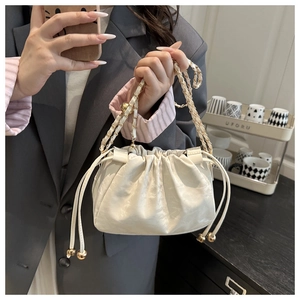 Détail du sac seau plissé blanc cassé avec bandoulière en chaîne dorée élégante