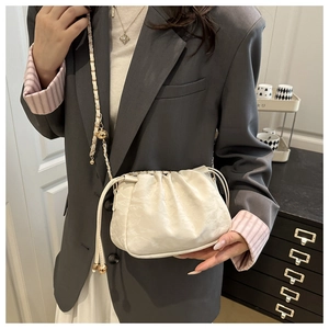 Détail du sac seau blanc cassé à cordon avec chaîne dorée et breloque sphérique