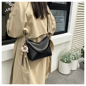 Détail d'un sac hobo en cuir grainé noir avec un pendentif mouton en peluche en extérieur