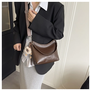 Détail du sac hobo en cuir PU marron foncé avec bandoulière jacquard et pendentif ours