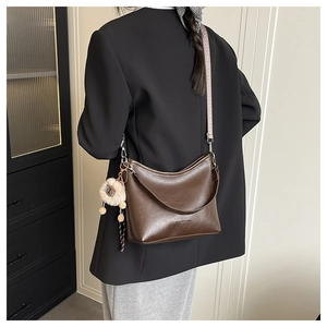 Gros plan du sac en cuir marron avec sangle en tricot et pendentif ours