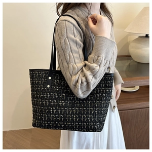 Détail du sac cabas en tweed montrant le tissage noir et or et les anses en cuir