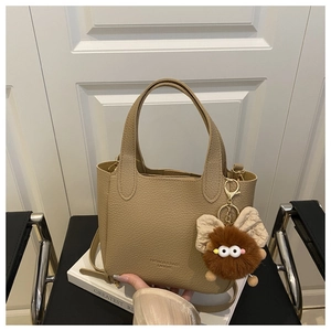 Détail du sac seau beige en cuir grainé avec un porte-clés en peluche doux