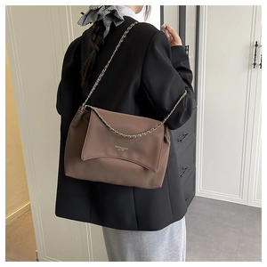 Brown leather tote bag featuring a silver metal chain strap shown on a female model