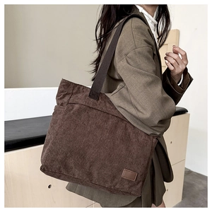 Detail of deep brown corduroy tote bag with durable shoulder strap and minimalist patch