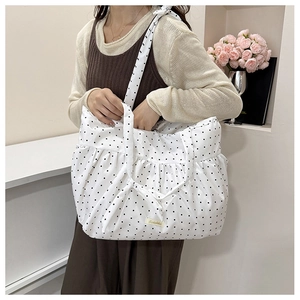 Detail of white polka dot tote bag with pleated edge and shoulder bow decoration