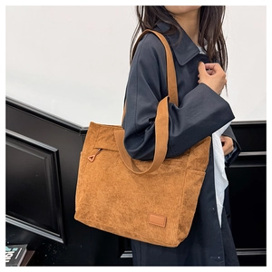 Detail of brown corduroy tote bag featuring a front zipper pocket and side pocket storage