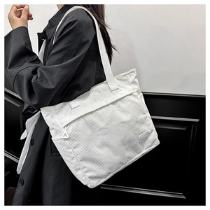 Close-up of white corduroy tote bag showing side pocket and front zipper detail