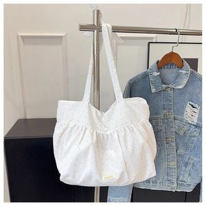 Detailed view of white polka dot tote bag featuring ruffled canvas fabric on hanger