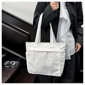 Detail of white corduroy tote bag showing side pocket and striped texture on the strap