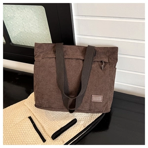 Detailed view of dark brown corduroy tote bag showing thick ribbed texture and straps