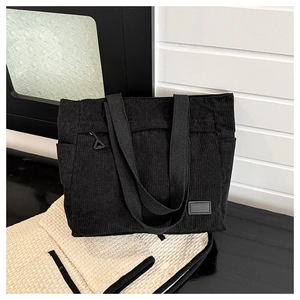 Detail of black corduroy tote bag showing ribbed texture and side pocket on cushion