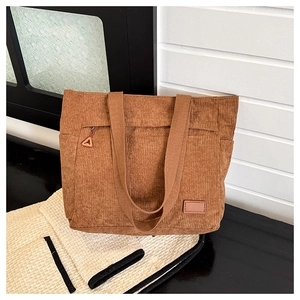 Close-up of brown corduroy tote bag featuring vertical texture and front zipper pocket