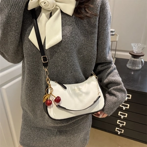 White lychee pattern shoulder bag with black trim and cherry charm on female model