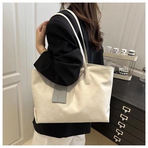 Close-up of creamy white faux leather tote bag showing fine texture and long straps