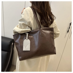 Detailed view of the textured brown faux leather tote bag with decorative beige tag