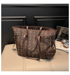 Detail of vintage brown monogram tote bag with matching round coin purse on a leather chair