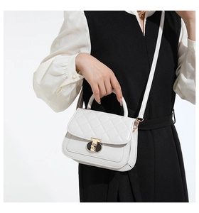 Detail van witte gewatteerde handtas met gouden metalen slot en elegante handgreep