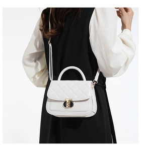 Detail van een witte gewatteerde PU-leren crossbodytas met gouden T-slot bij een model