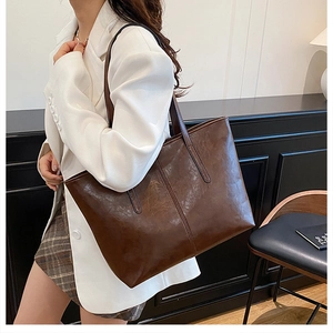 Brown vintage oily leather tote bag with vertical stitching shown on model shoulder