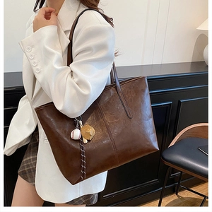 Detail of dark brown tote bag in oily faux leather with baseball glove charm and large capacity