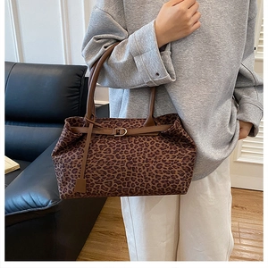 Detailed view of leopard print tote bag featuring a leather strap and gold buckle