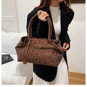 Close-up of leopard print tote bag featuring leather handles and vintage metal buckles