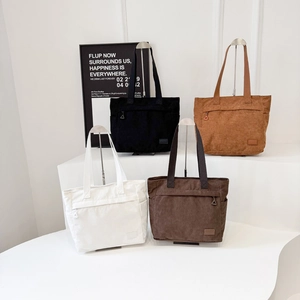 Large corduroy tote bags in black, white, brown, and dark coffee on a display stand