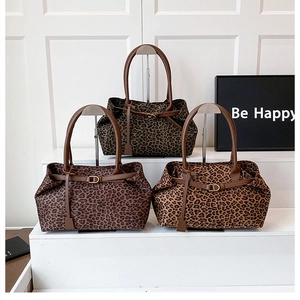 Three variations of leopard print suede tote bags displayed on minimalist metal stands