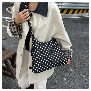 Close-up of black and white polka dot tote bag with an adjustable nylon shoulder strap