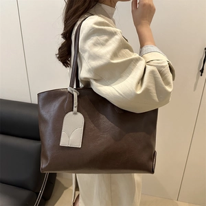 Minimalist dark brown leather tote bag with cream charm accessory for office daily use