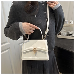 Detail of cream white handbag featuring geometric stitching and gold metal lock clasp