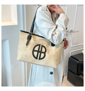 Detailed close-up of large tote bag with black leather shoulder straps and round logo