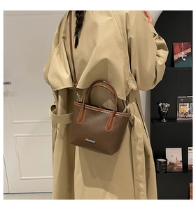 Brown lychee leather bucket bag with top handle and shoulder strap shown in life scene