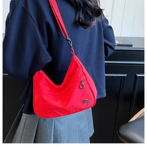 Vue détaillée d'un sac bandoulière en nylon rouge avec logo M argenté et sangle réglable