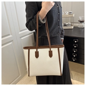 Macro detail of the woven texture and brown leather trim on the white tote bag