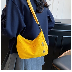 Detail of yellow waterproof nylon crossbody bag with adjustable strap and metal logo