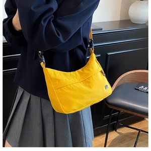 Détail du sac demi-lune en nylon jaune avec poche avant et sangle à boucle noire