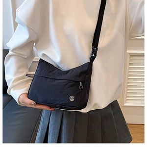 Détail d'une besace minimaliste en nylon noir avec logo métallique rond argenté M