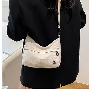 Détail du sac bandoulière blanc cassé plissé avec sangle réglable sur un mannequin