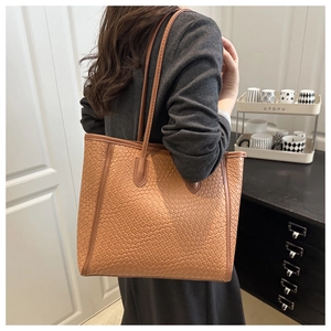 Detailed view of brown woven tote bag with slim shoulder straps for daily commute