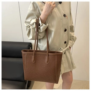 Detail of deep brown crocodile texture tote bag with woven pattern and leather strap