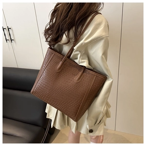 Close-up of dark brown tote bag featuring textured woven pattern and slim shoulder straps
