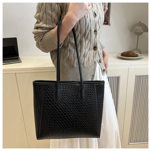 Close-up of black woven texture on a large tote bag held by a model in casual setting