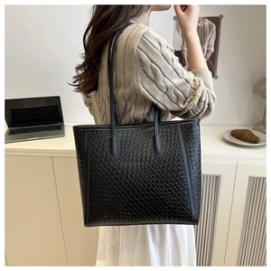 Close-up of black woven tote bag with premium crocodile texture and slim shoulder straps